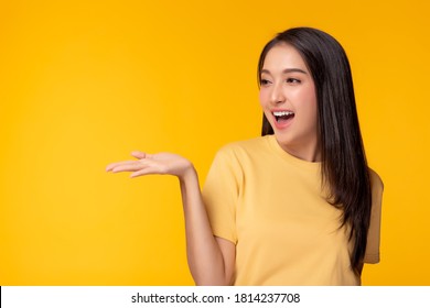 Happy beautiful young asian woman with yellow background holding copy space imaginary on beauty palm for insert advertisement, happiness and smiley face. Attractive beautiful girl portrait - Shutterstock ID 1814237708