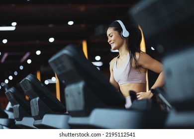 Happy beautiful young asian woman running on treadmill and listening to music via headphone during sports training in a gym. - Shutterstock ID 2195112541