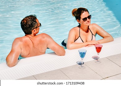 Happy And Beautiful Young Couple Drinking Champagne At Swimming Pool. Fun Romantic Lifestyle. Vacation Trip On Holiday Resort. Travel Together. Adult People Relax In Summer. Woman And Man.