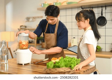 Happy beautiful young couple prepares a healthy drink in their modern kitchen. - Powered by Shutterstock