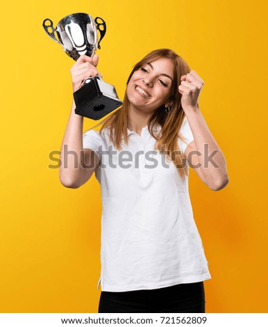 Happy Beautiful young girl holding a trophy on yellow background