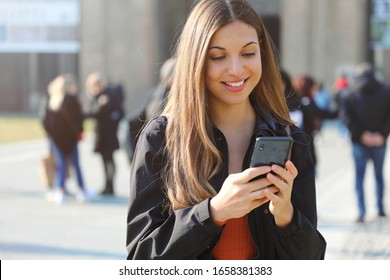 Happy Beautiful Young High School Girl With Smart Phone Outdoors On Sunny Spring Day Texting And Smiling