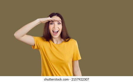 Happy Beautiful Young Woman In Casual Yellow T Shirt Isolated On Solid Brown Background Holding Her Hand On Her Forehead Like Visor And Looking In Distance With Cheerful Excited Face Expression