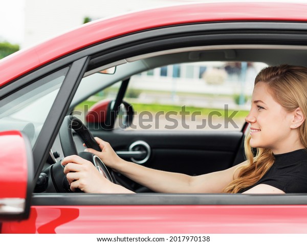 Happy beautiful young\
woman drives a car.