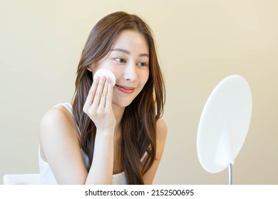 Happy Beauty, Beautiful Asian Young Woman, Girl Looking In To Mirror, Holding Cotton Pad, Applying Facial Wipe On Her Face, Removing Makeup Before Shower In Bathroom, Skin Care On White Background.