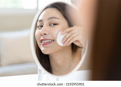 Happy Beauty, Beautiful Asian Young Woman, Girl Smiling, Looking In Mirror, Holding Cotton Pad, Applying Lotion By Wipe On Her Face, Removing Makeup Before Shower At Home. Skin Care Routine People.