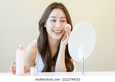 Happy Beauty, Beautiful Asian Young Woman, Girl Looking In To Mirror, Holding Cotton Pad, Applying Facial Wipe On Her Face, Removing Makeup Before Shower In Bathroom, Skin Care On White Background.