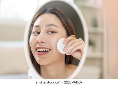 Happy Beauty, Beautiful Asian Young Woman, Girl Smiling, Looking In Mirror, Holding Cotton Pad, Applying Lotion By Wipe On Her Face, Removing Makeup Before Shower At Home. Skin Care Routine People.