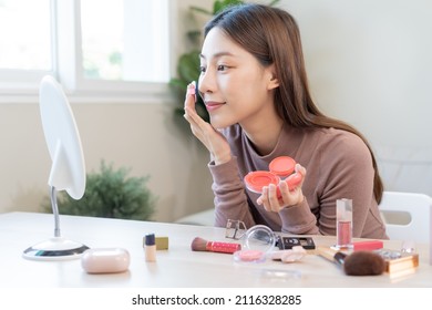 Happy Beauty Blogger Concept, Pretty Asian Young Woman, Girl Make Up Face By Applying Pink Blush By Brush On Cheek, Looking At The Mirror On Table At Home. Female Look With Natural Fashion Style.