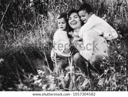 happy beauty family of smiling mother sitting on trail and two young boys hugging, kids and mom
