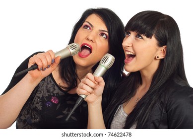 Happy Beauty Two Women Singing In Microphones At Karaoke Party And Looking Up To Screen Isolated On White Background