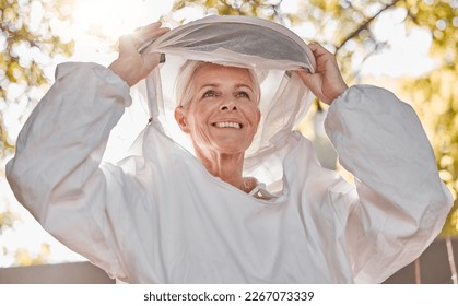 Happy, beekeeper and woman in nature for honey collection, monitor beehive health or check backyard environment. Smile, agriculture and senior apiarist in safety gear ready to start garden inspection - Powered by Shutterstock