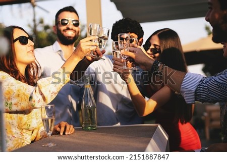 Happy best friends at terrace party toasting with Prosecco white wine in a summer afternoon - young people clinking flutes and having fun - trendy people carefree in the weekend at rooftop party