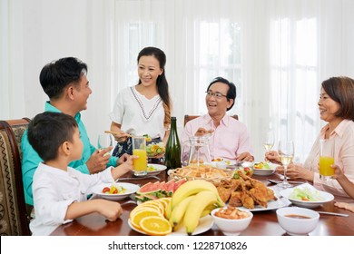 Happy Big Asian Family Eating At Talking At Big Dinner Table