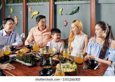 Happy Big Asian Family Enjoying Dinner In Restaurant Together And Eating Traditional Dishes