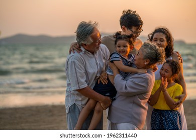 Happy Big Asian Family On Beach Holiday Vacation. Multi-generation Family Holding Hands And Walking Together On Tropical Beach At Summer Sunset. Family Enjoy And Having Fun Outdoor Activity Lifestyle.