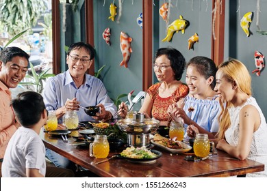 Happy Big Asian Family Talking, Laughing And Eating Good Food At Dinner