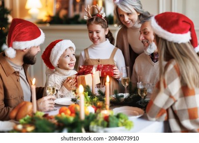 Happy big family with children on Christmas morning at home, cute little kids boy and girl hold xmas gift boxes while gathering with parents and grandparents during festive dinner. Winter holidays - Powered by Shutterstock