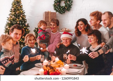 Happy Big Family At Christmas Dinner. Children Are Happy New Year Holding Sparklers In Their Hands