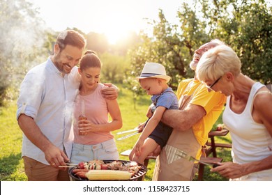 Happy big family gathered around the grill at picnic.Leisure,food,family and holidays concept. - Powered by Shutterstock