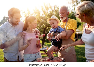 Happy Big Family Gathered Around The Grill At Picnic.Leisure,food,family And Holidays Concept.