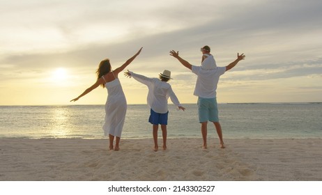 Happy Big Family On Beach Holiday Vacation. Family Holding Hands And Walking Together On Tropical Beach At Summer Sunset. Family Enjoy And Having Fun Outdoor Activity Lifestyle