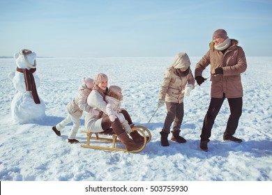 Happy Big Family Sled Near A Snowman In Winter