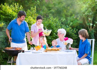 Happy Big Family - Young Mother And Father With Kids, Teen Age Son, Cute Toddler Daughter And A Little Baby, Enjoying Bbq Lunch With Grandmother Eating Grilled Meat In The Garden With Salad And Bread