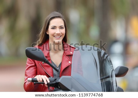 Happy biker posing looking at camera sitting on her motorbike on the street