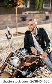 Happy biker smiling while sitting on his parked motorcycle in a paved city street during a sunny day