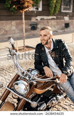 Happy biker smiling while sitting on his parked motorcycle in a paved city street during a sunny day