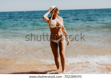 Happy bikini woman having fun swimming in ocean. Freedom bikini woman carefree with arms up splashing water in joy on tropical beach.
