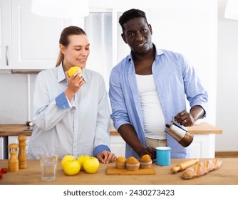 Happy biracial couple laughing and drinking coffee - Powered by Shutterstock