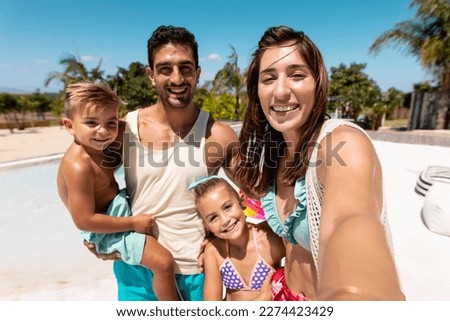 Happy biracial family taking selfie by the swimming pool. Spending quality time, lifestyle, family, summertime and vacation concept.