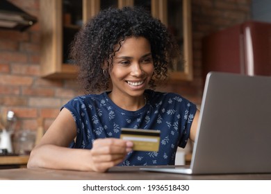 Happy Biracial Female Vip Bank Customer Pay Online Buy Goods At Internet Shop Using Gold Card For Web Payment. Smiling Successful Young Black Woman Look At Laptop Screen Check Balance In E-banking App