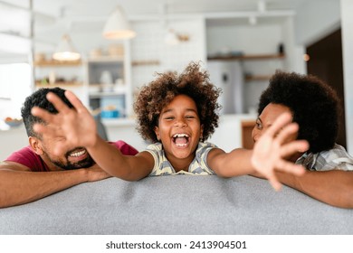 Happy biracial girl smiling with young multiracial parents enjoy weekend at home together, - Powered by Shutterstock