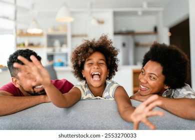 Happy biracial girl smiling with young multiracial parents enjoy weekend at home together, - Powered by Shutterstock