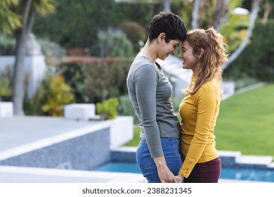 Happy biracial lesbian couple on garden terrace holding hands and touching heads, copy space. Love, gay, relationship, togetherness, domestic life and lifestyle, unaltered. - Powered by Shutterstock