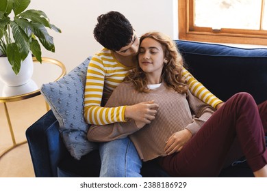 Happy biracial lesbian couple relaxing on couch together embracing at home. Gay, love, relationship, togetherness, domestic life and lifestyle, unaltered. - Powered by Shutterstock