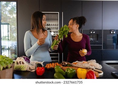 Happy biracial lesbian couple unpacking groceries in kitchen. Shopping, food, healthy lifestyle, lifestyle, relationship, togetherness and domestic life, unaltered. - Powered by Shutterstock