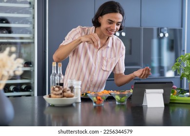 Happy biracial man cooking and using tablet in kitchen. Spending quality time at home alone, domestic life and lifestyle concept. - Powered by Shutterstock