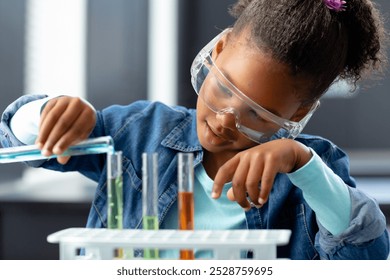 Happy biracial schoolgirl in safety glasses doing experiment in science class with copy space. Education, inclusivity, childhood, elementary school and learning concept. - Powered by Shutterstock