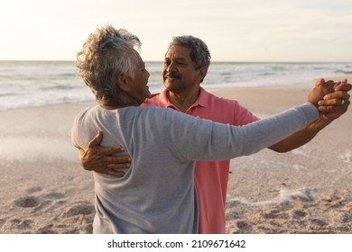 Happy biracial senior man enjoying romantic dance with woman at beach during sunset. lifestyle, love and weekend. - Powered by Shutterstock