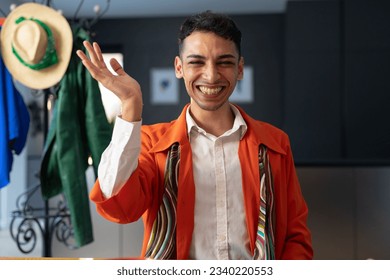 Happy biracial transgender fashion designer sitting at desk, waving and having video call. Gender, fashion, design, communication and lifestyle, unaltered. - Powered by Shutterstock