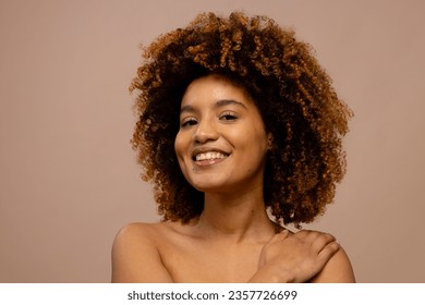 Happy biracial woman with dark curly hair, smiling with hand on shoulder. Femininity, face, facial expressions, body, skin and beauty, unaltered. - Powered by Shutterstock
