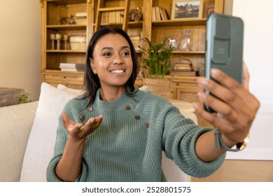 Happy biracial woman making video call using smartphone in living room. Lifestyle, relaxation and communication. - Powered by Shutterstock