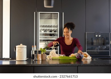 Happy biracial woman unpacking groceries in kitchen. Shopping, food, healthy lifestyle, lifestyle and domestic life, unaltered. - Powered by Shutterstock