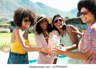 Happy Biracial Young Female Friends Toasting Cocktails While Having Fun At Pool Party In Summer. Hangout, Drink, Unaltered, Friendship, Togetherness, Social Gathering, Enjoyment, Weekend Activities.