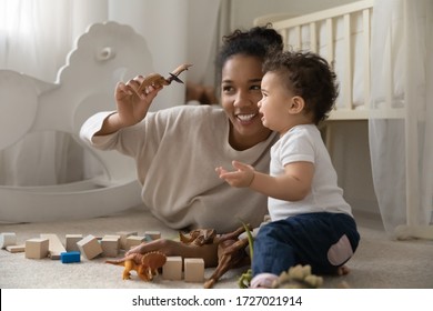 Happy Biracial Young Mom Sit Relax On Floor At Home Playing With Little Baby Girl With Toys, Smiling African American Mother Engaged In Game Activity With Small Toddler Or Infant, Motherhood Concept