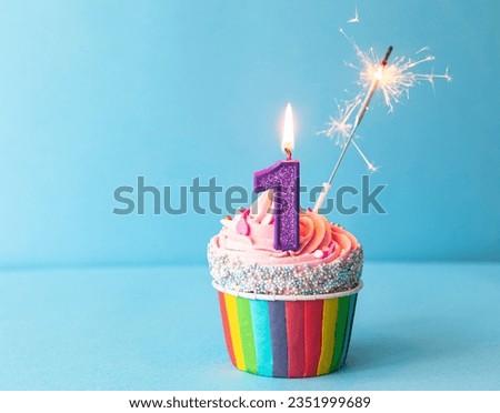 Happy Birthday 1st Birthday Cupcake
Purple number one candle, pink frosting, blue background with sparkler and rainbow cupcake case  